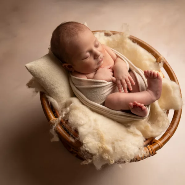 éance photo naissance en studio avec un nouveau-né emmailloté, entouré de sa famille, capturée dans un décor naturel et doux entre Montpellier et Béziers.