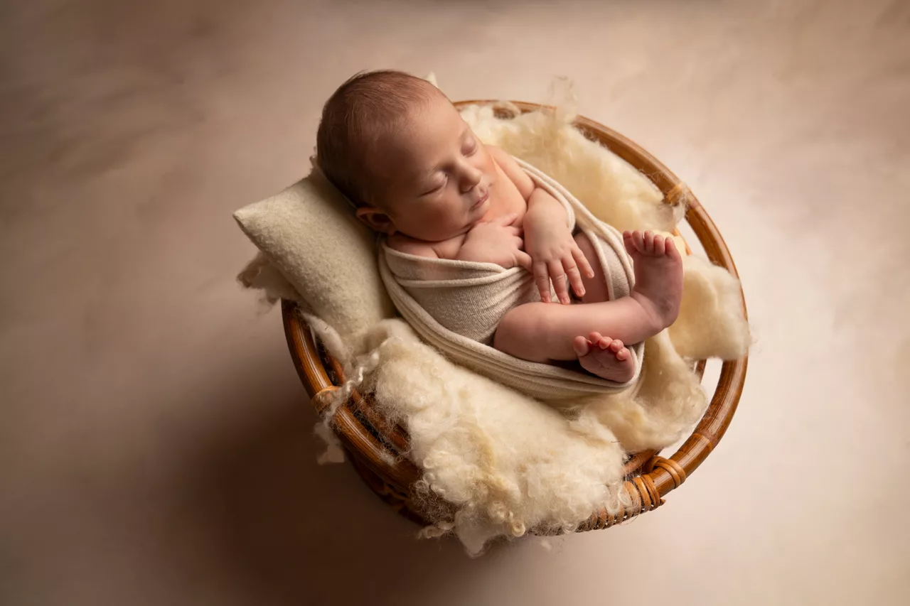 éance photo naissance en studio avec un nouveau-né emmailloté, entouré de sa famille, capturée dans un décor naturel et doux entre Montpellier et Béziers.
